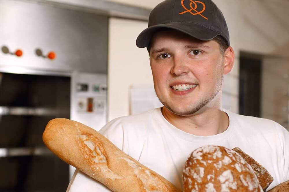Bäcker der Calenberger Backstube hält Brote im Arm