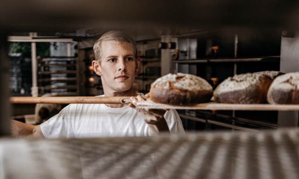 Auszubildender Bäcker der Bäckerei & Konditorei Schrunz bei der Arbeit in der Backstube in Münster