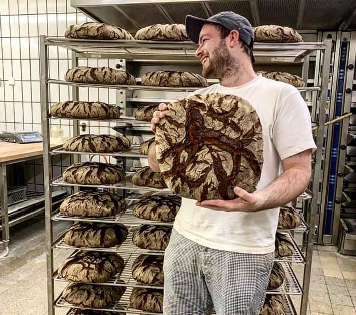 Bäcker der Bäckerei Benslips hält ein Brot