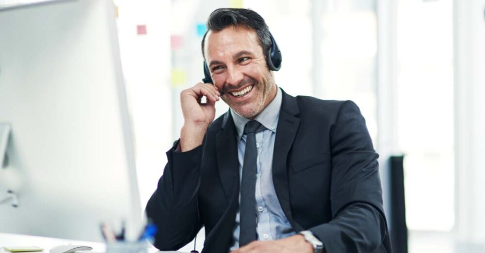 Vertriebsmitarbeiter sitzt am Schreibtisch und telefoniert mit seinem Headset.